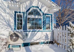 air source heat pump outside of a snowy home window